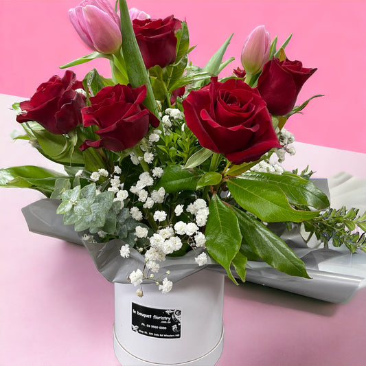 8 red roses and 4 Tulip in Cuddle Bucket arrangement